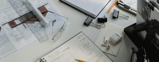 A busy architectural workspace featuring blueprints, sketches, and drafting tools.